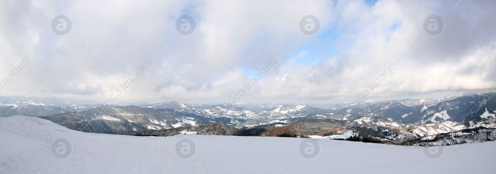 Image of Picturesque mountain landscape with snowy hills under cloudy sky. Banner design