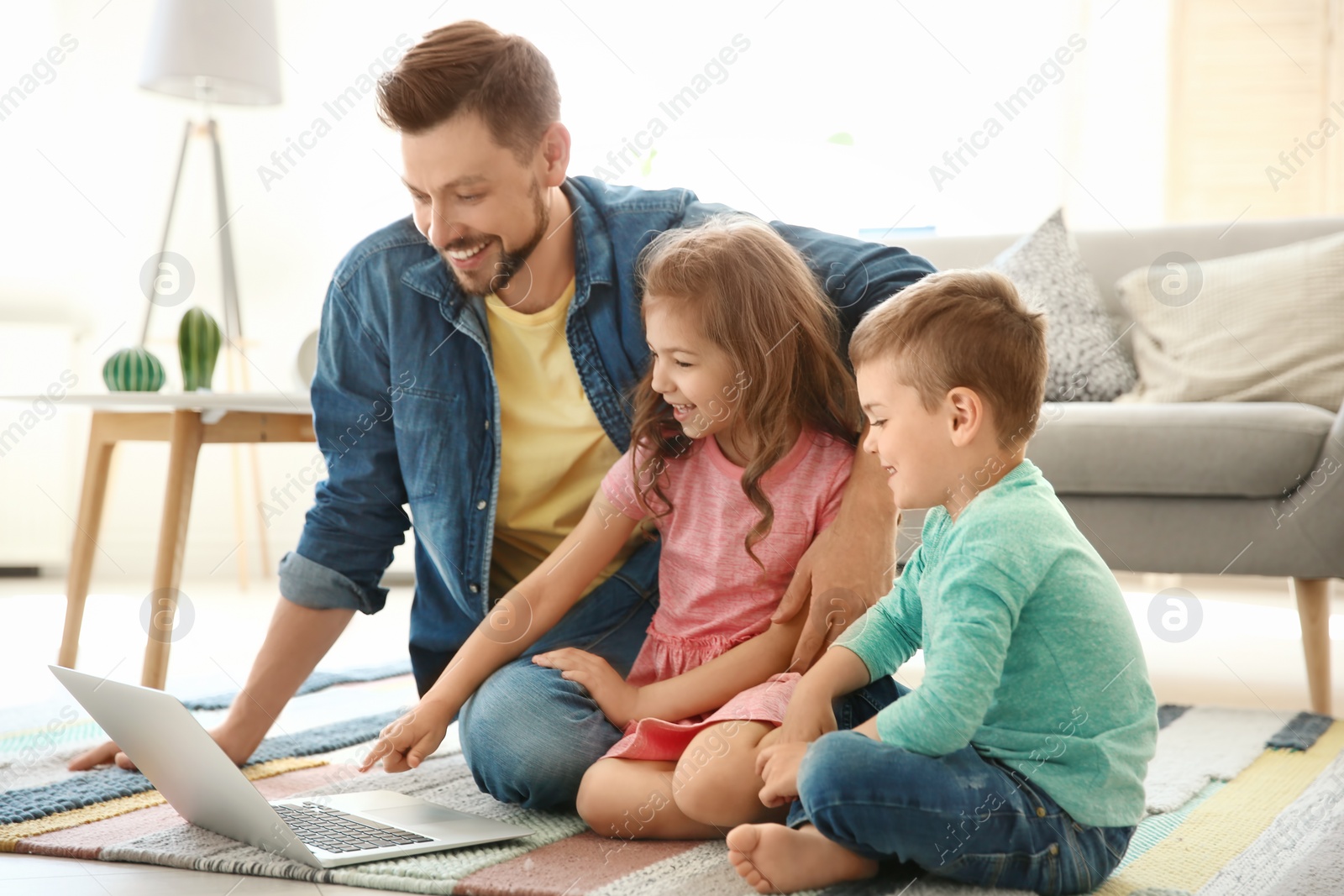 Photo of Young man using laptop with children at home. Happy family