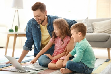 Young man using laptop with children at home. Happy family