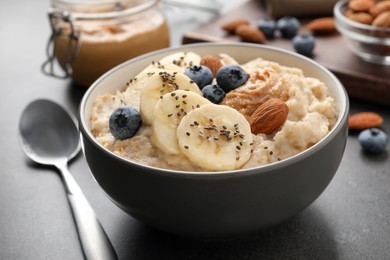 Photo of Tasty oatmeal porridge with toppings served on table, closeup