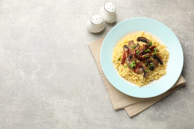 Photo of Tasty millet porridge with mushrooms, bacon and green onion on grey textured table, top view. Space for text