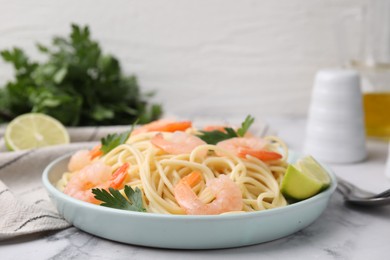 Photo of Tasty spaghetti with shrimps, lime and parsley on white marble table, closeup