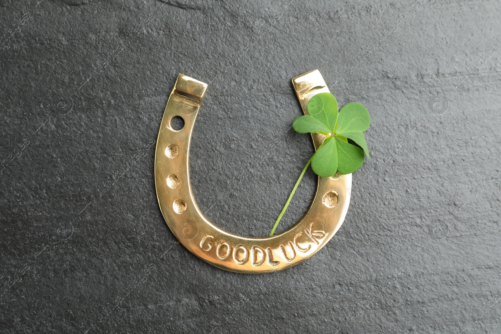 Photo of Clover leaf and horseshoe on grey stone table, flat lay. St. Patrick's Day celebration