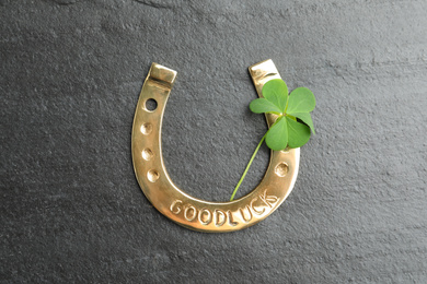 Photo of Clover leaf and horseshoe on grey stone table, flat lay. St. Patrick's Day celebration