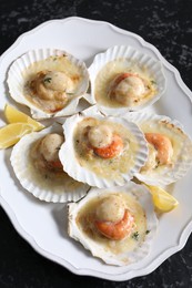 Photo of Fried scallops in shells and lemon on black textured table