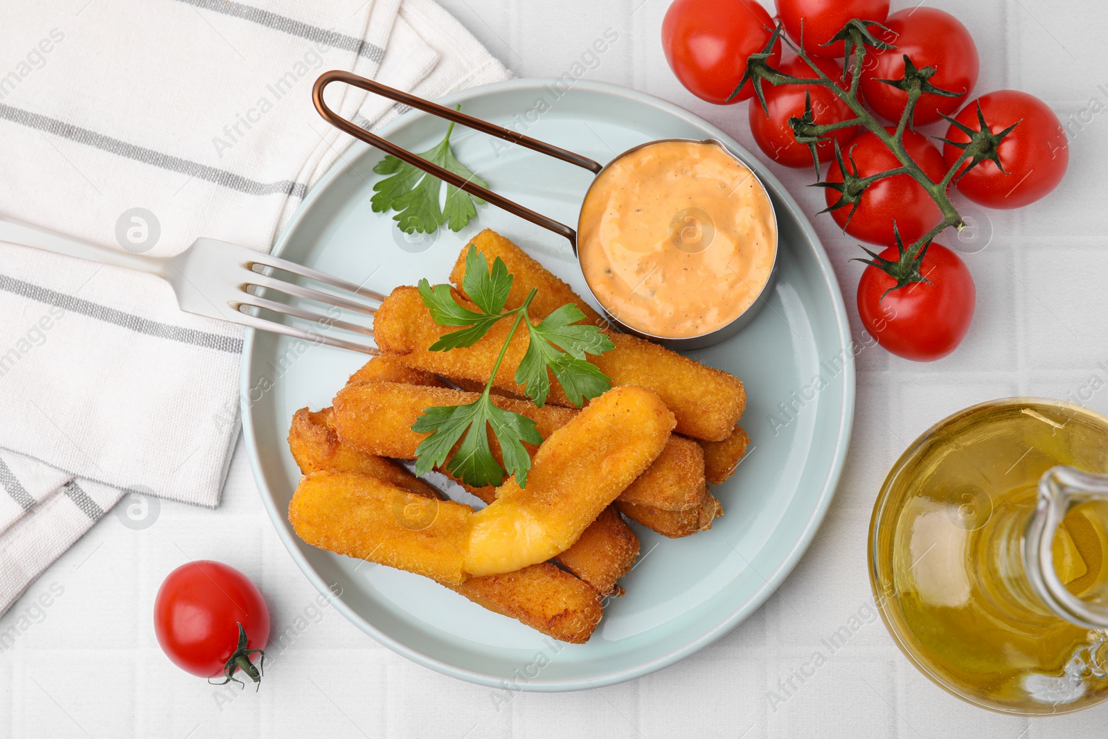 Photo of Tasty fried mozzarella sticks served with sauce on white tiled table, flat lay