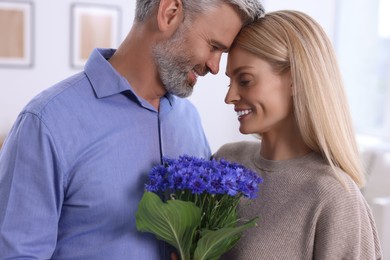 Photo of Happy affectionate couple with bouquet of cornflowers at home. Romantic date