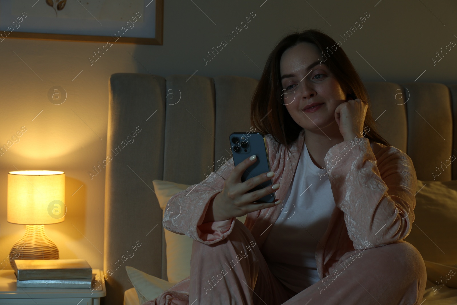 Photo of Woman using smartphone in bedroom at night. Internet addiction