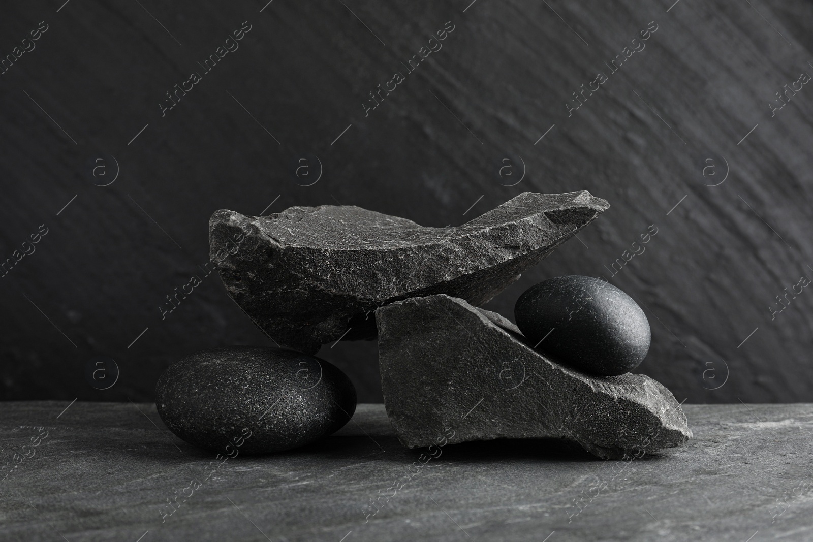 Photo of Presentation for product. Podium made of different stones on grey textured background