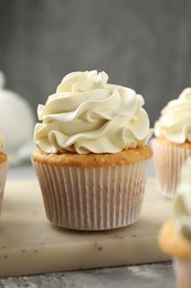 Tasty cupcakes with vanilla cream on grey table, closeup