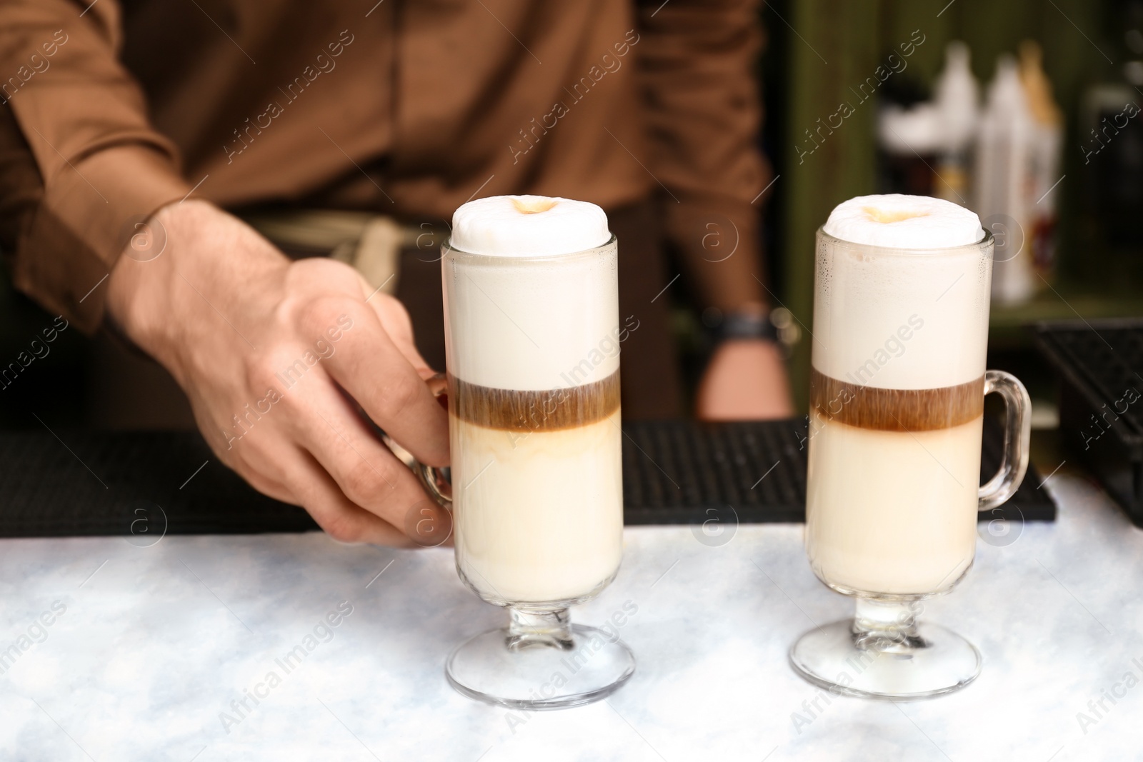 Photo of Barista serving tasty coffee drink on table, closeup view