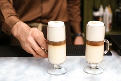 Barista serving tasty coffee drink on table, closeup view