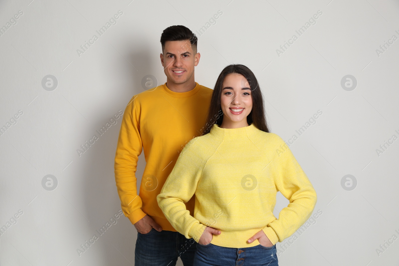 Photo of Happy couple wearing yellow warm sweaters on white background