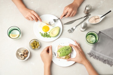 Women having breakfast with avocado at table, top view