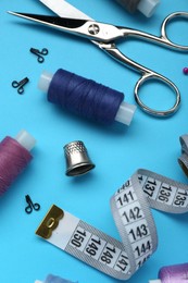 Thimble and different sewing tools on light blue background, above view
