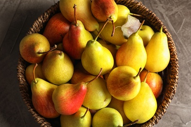 Photo of Wicker bowl with ripe pears on grey background, top view