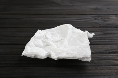 Photo of Crumpled paper napkin on wooden table. Personal hygiene