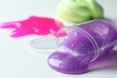 Overturned plastic container with purple slime on white background, closeup. Space for text