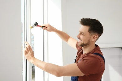 Professional construction worker installing plastic window indoors