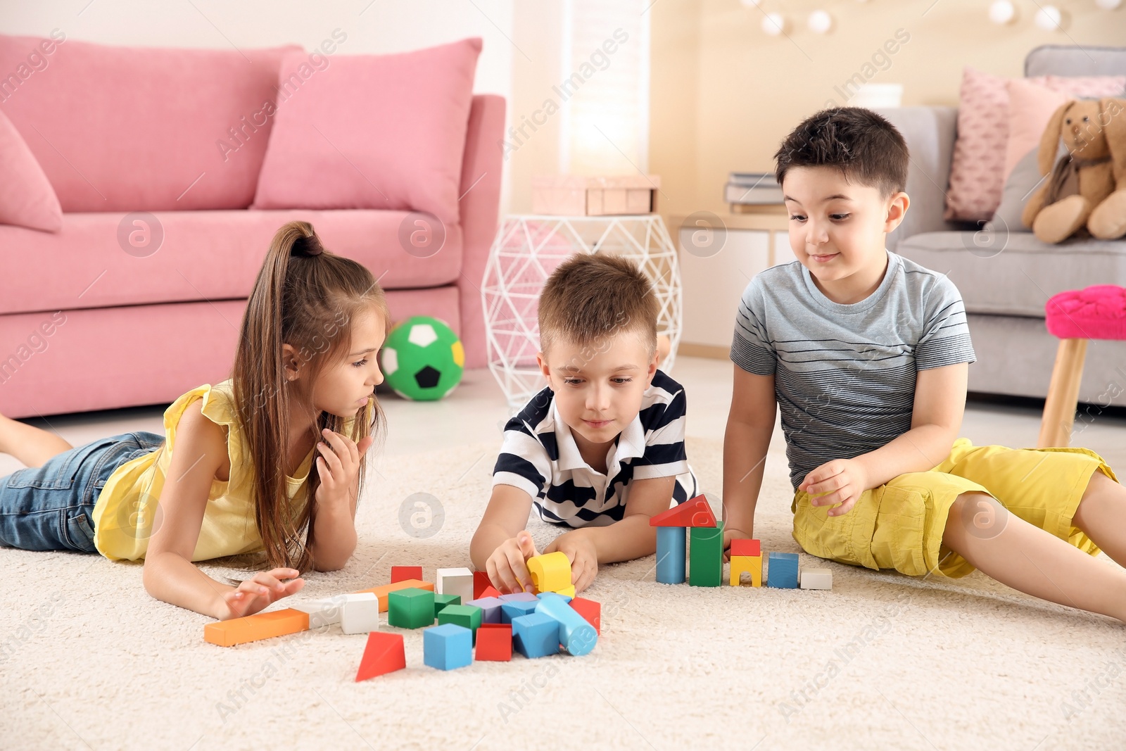 Photo of Cute little children playing with building blocks on floor, indoors