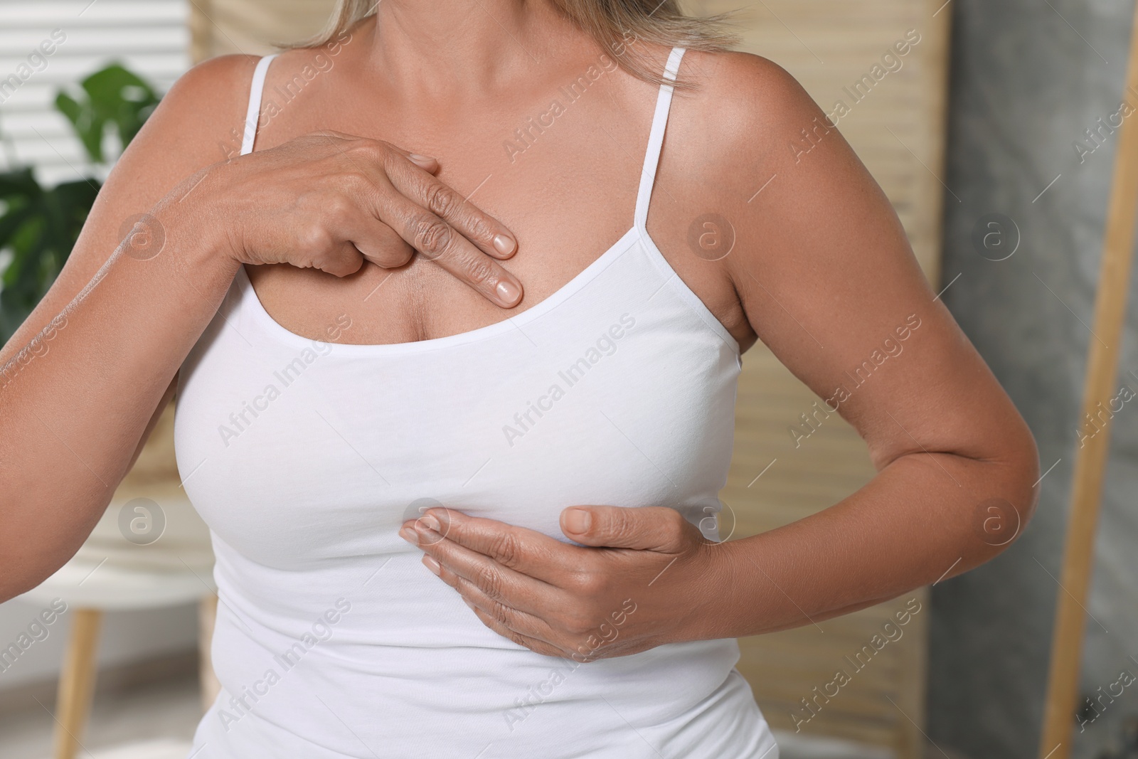 Photo of Woman doing breast self-examination in bathroom, closeup