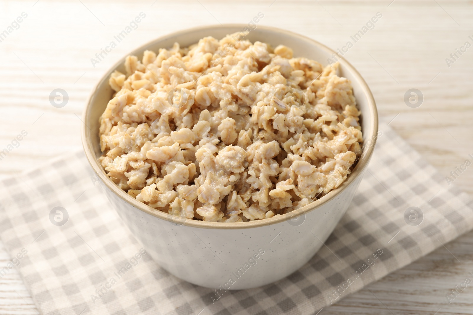 Tasty boiled oatmeal in bowl on light wooden table, closeup Photo of Tasty boiled oatmeal in bowl on light wooden table, closeup