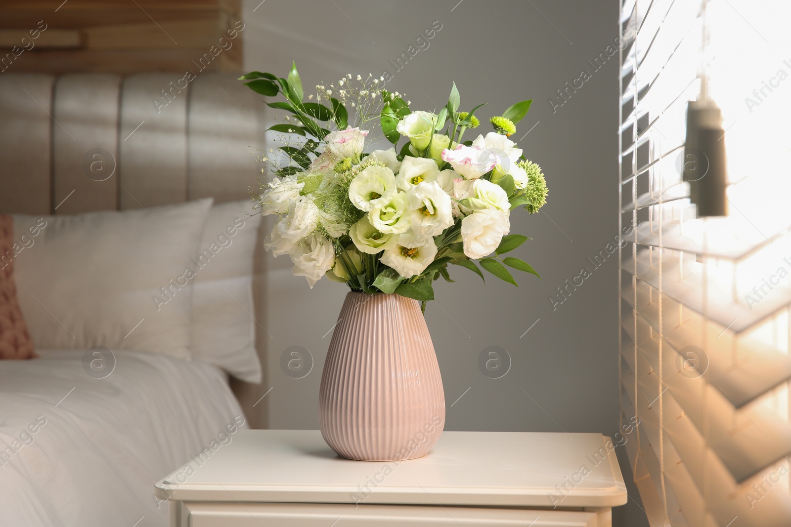Photo of Bouquet of beautiful flowers on nightstand in bedroom. Interior design