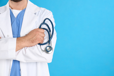 Photo of Closeup view of mature doctor with stethoscope on blue background, space for text