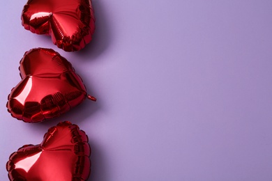 Photo of Red heart shaped balloons on violet background, space for text. Valentine's Day celebration