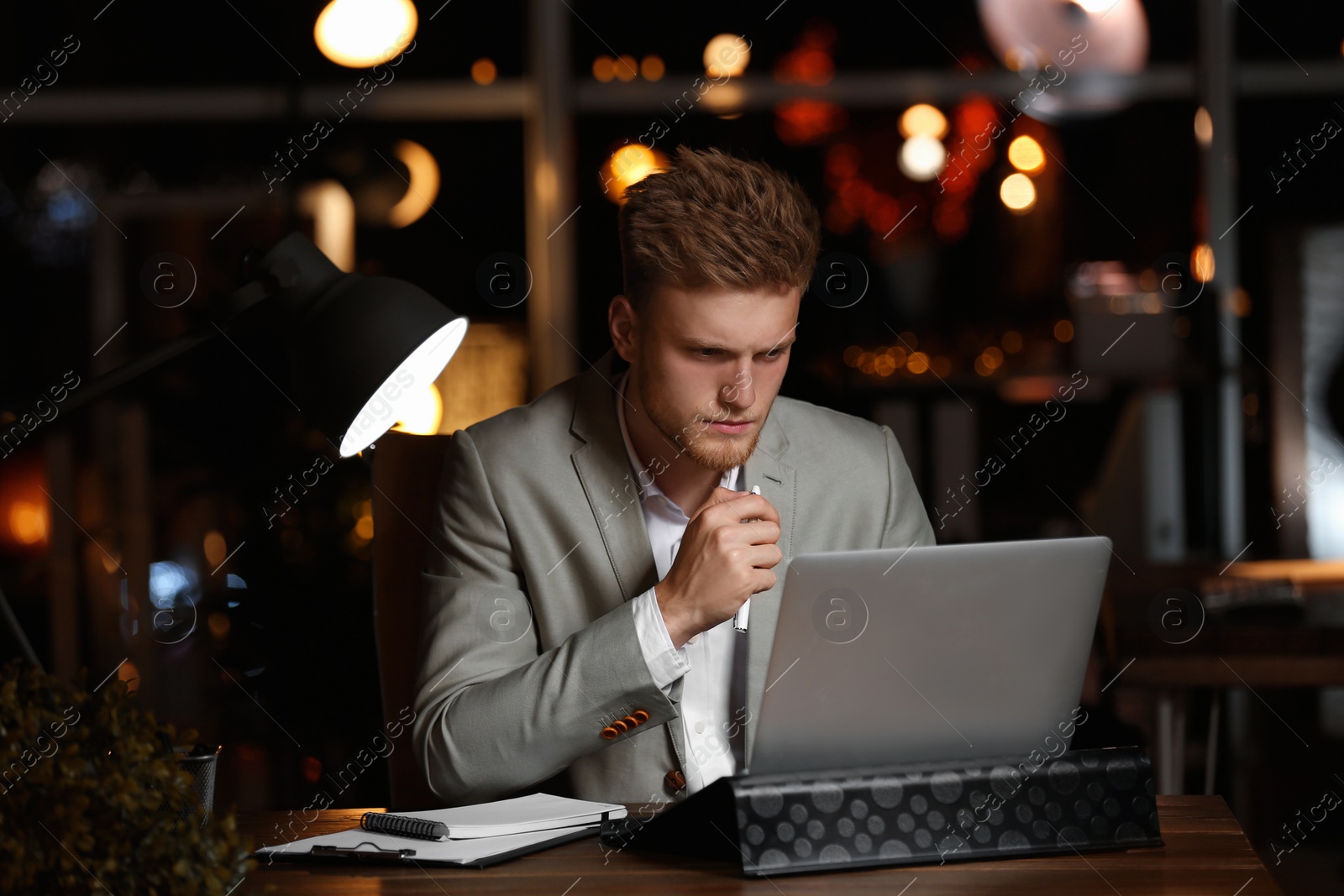 Photo of Young man working in office at night