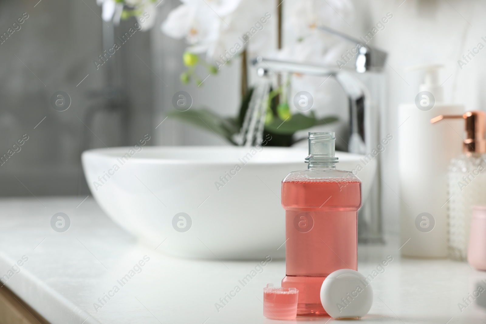 Photo of Mouthwash and dental floss on white countertop in bathroom. Space for text