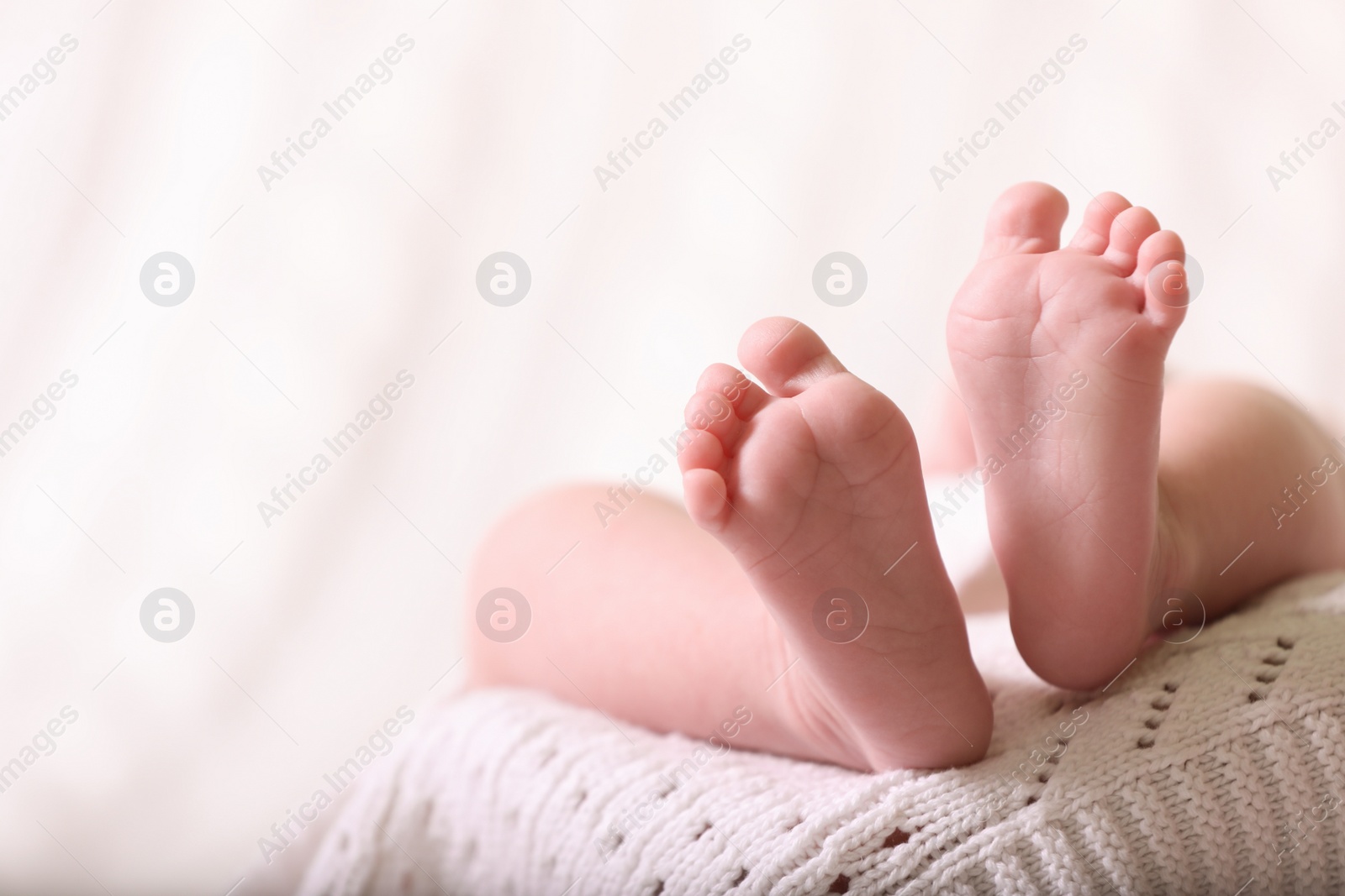 Photo of Cute newborn baby lying on white knitted plaid, closeup of legs. Space for text