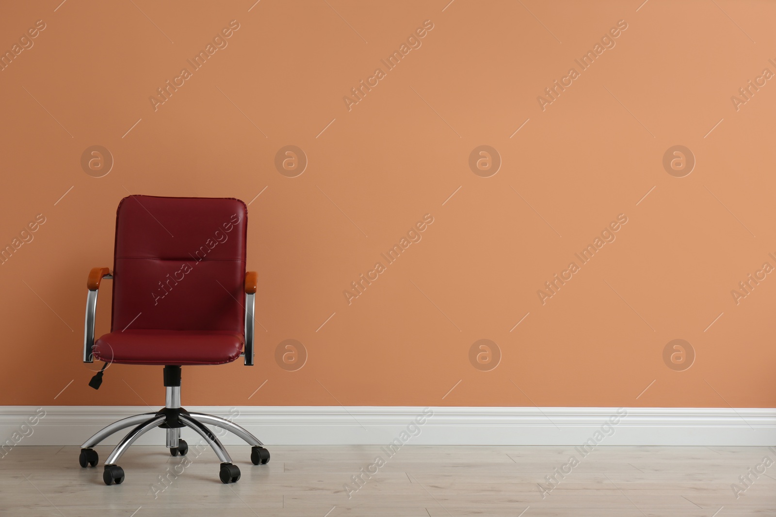 Photo of Modern office chair near orange coral wall indoors. Space for text