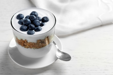 Photo of Glass with yogurt, berries and granola on table