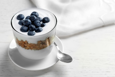 Glass with yogurt, berries and granola on table