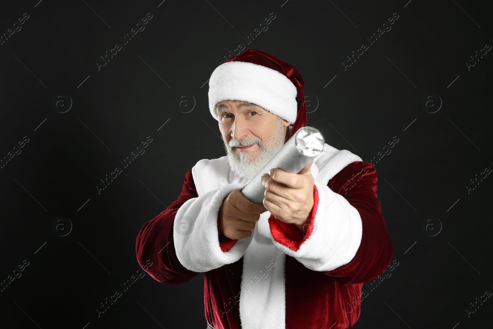 Photo of Man in Santa Claus costume with party popper on black background