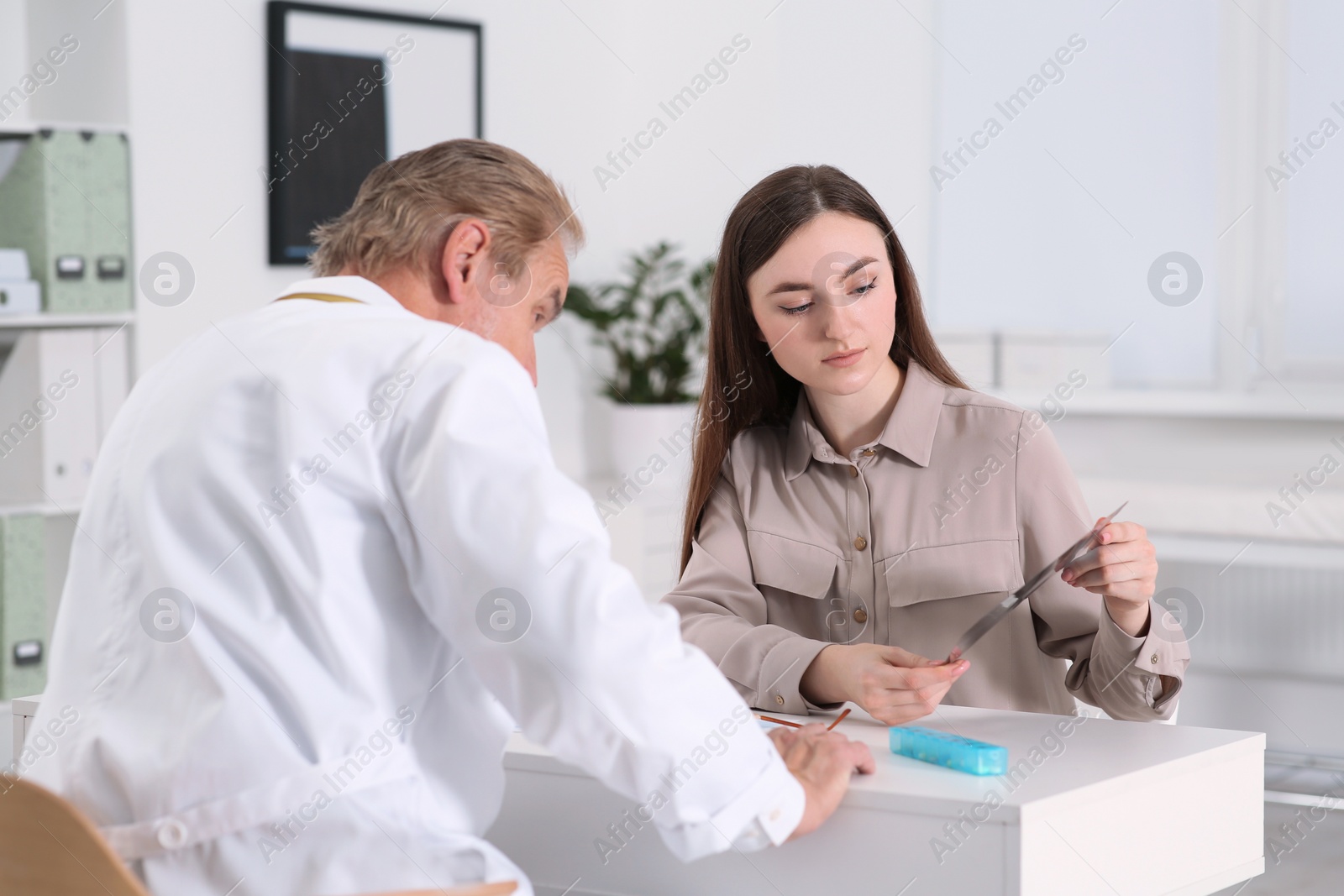 Photo of Professional orthopedist consulting patient at table in clinic