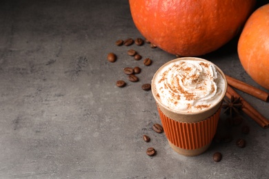 Photo of Paper cup with tasty pumpkin spice latte and space for text on gray table