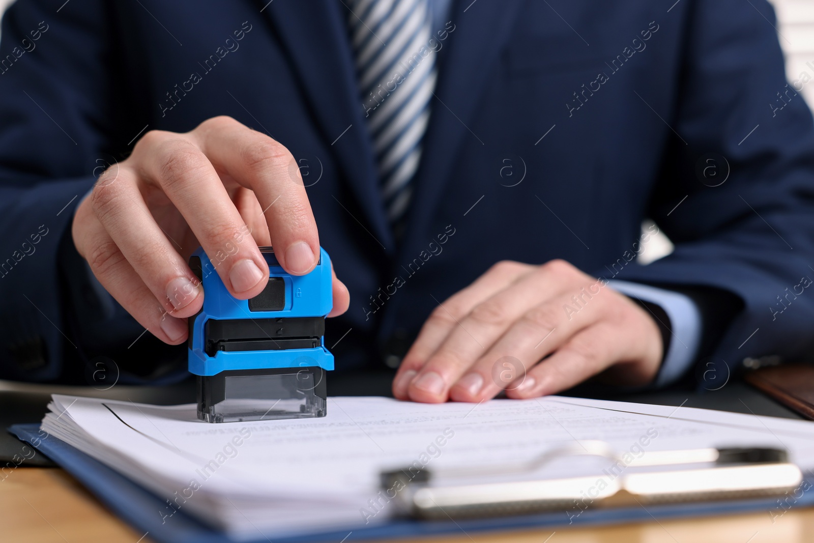 Photo of Notary stamping document at table, closeup view