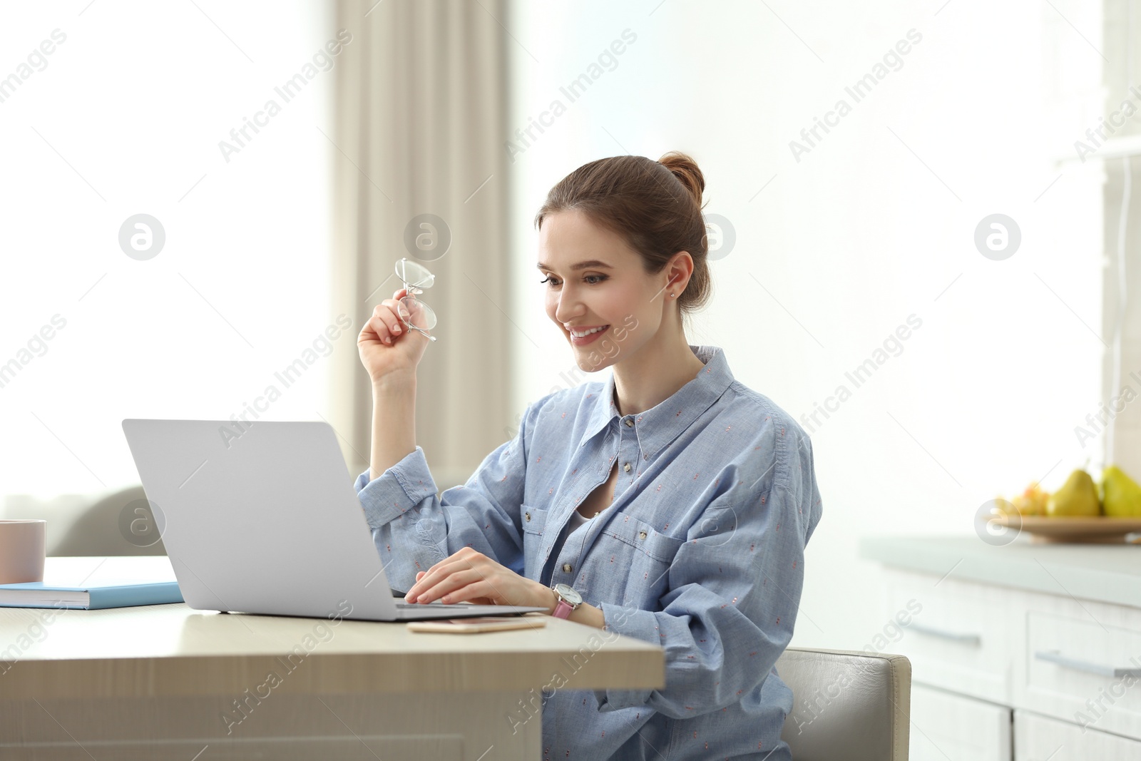 Photo of Young woman using laptop at table indoors