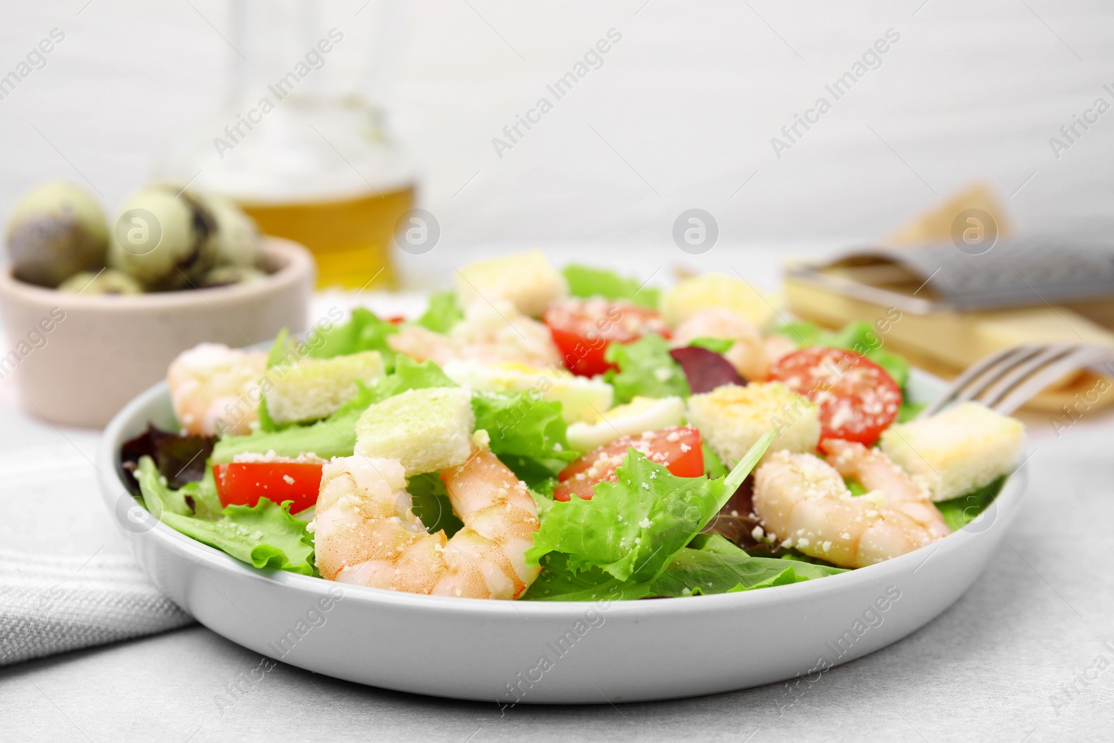 Photo of Delicious Caesar salad with shrimps on light table, closeup