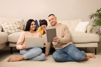 Photo of Happy family with gadgets on floor at home