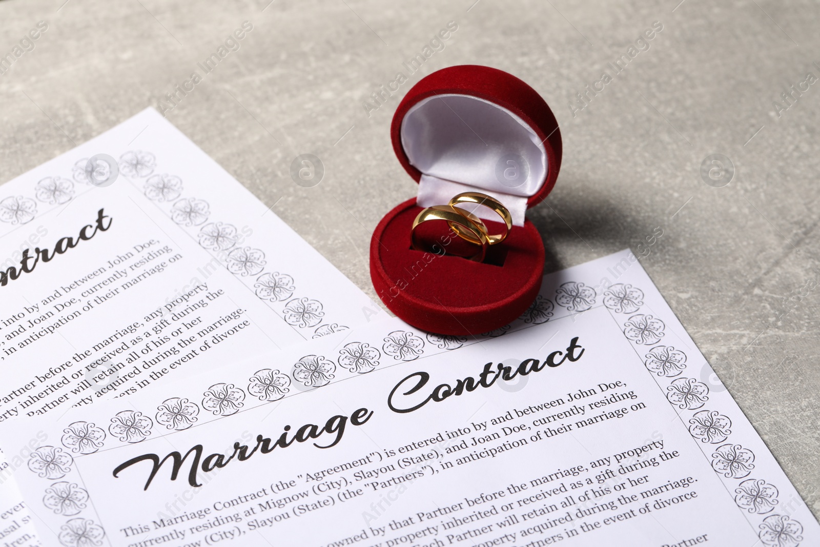 Photo of Marriage contract and golden wedding rings on grey table