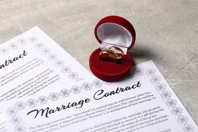 Photo of Marriage contract and golden wedding rings on grey table