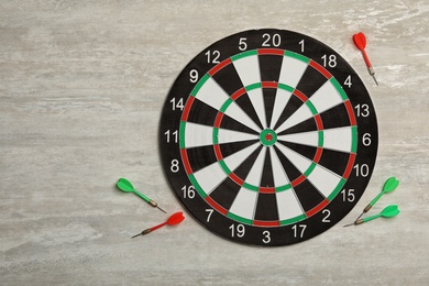 Dart board with color arrows on light stone background, top view. Space for text