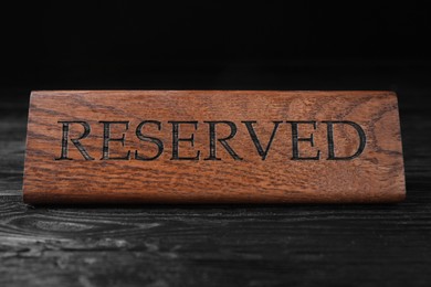 Photo of Elegant wooden sign RESERVED on black table