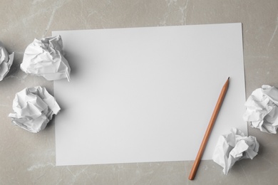 Blank sheet, pencil and crumpled paper balls on grey marble table, flat lay. Space for text