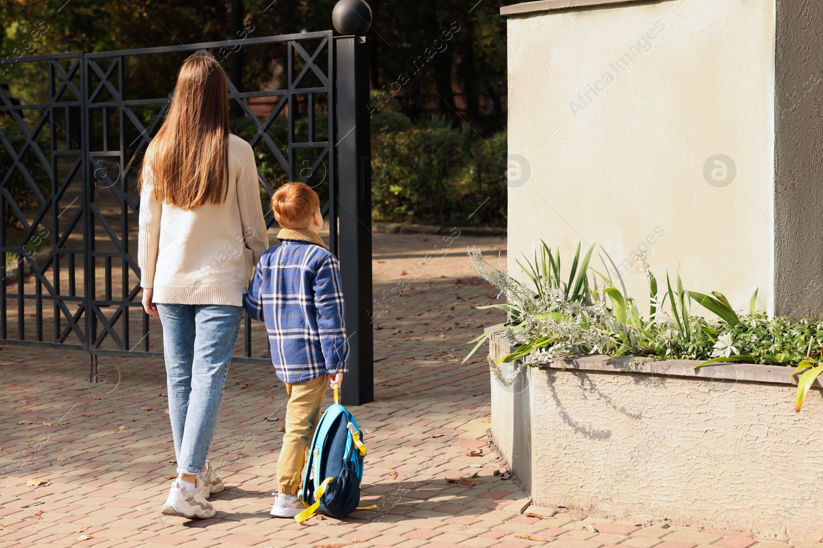 Photo of Young mom taking her son to school, back view