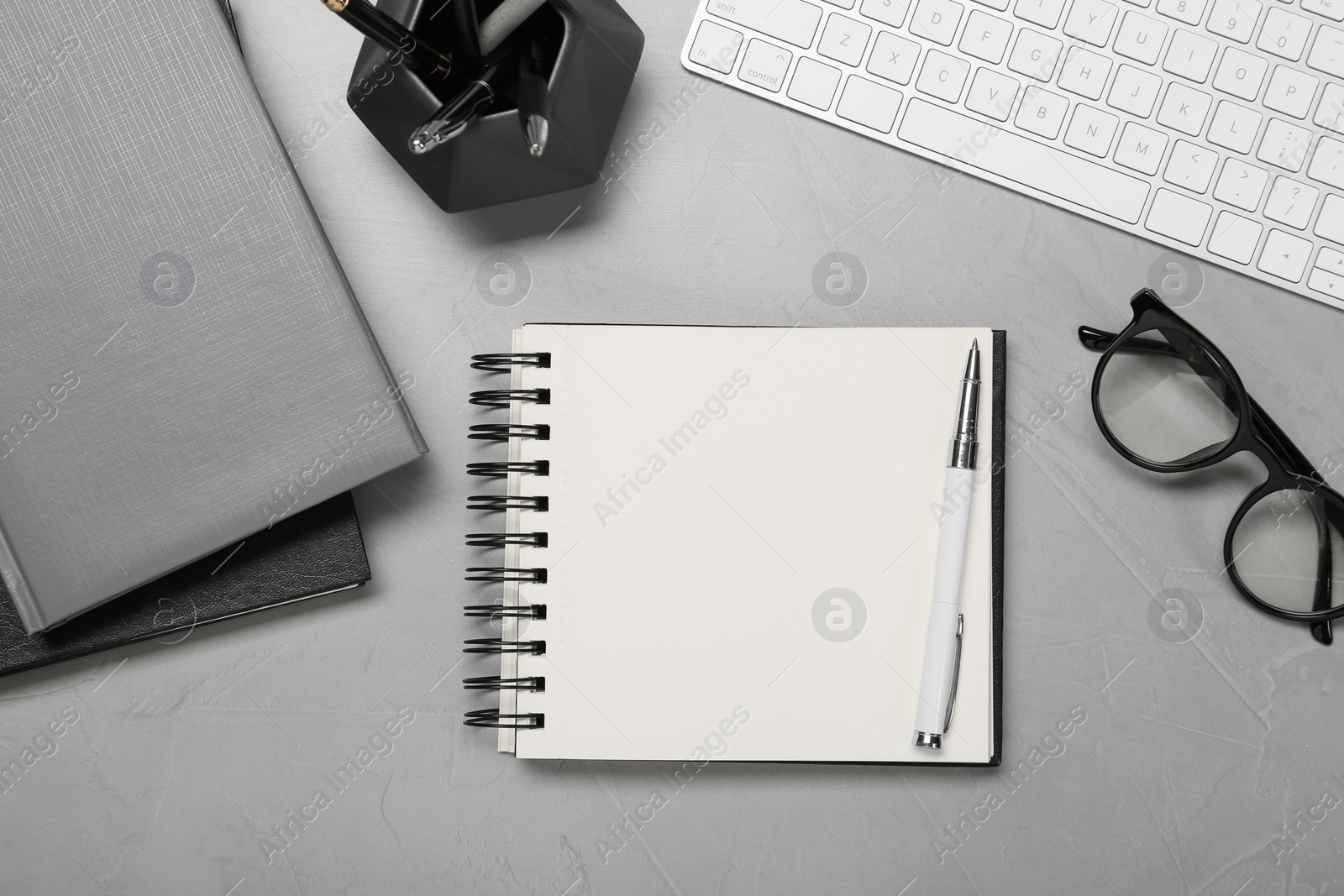 Photo of Flat lay composition with notebooks, keyboard and glasses on light grey table