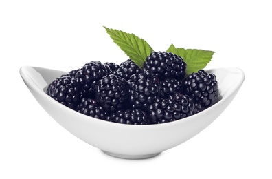 Photo of Ceramic bowl of tasty ripe blackberries and leaves on white background